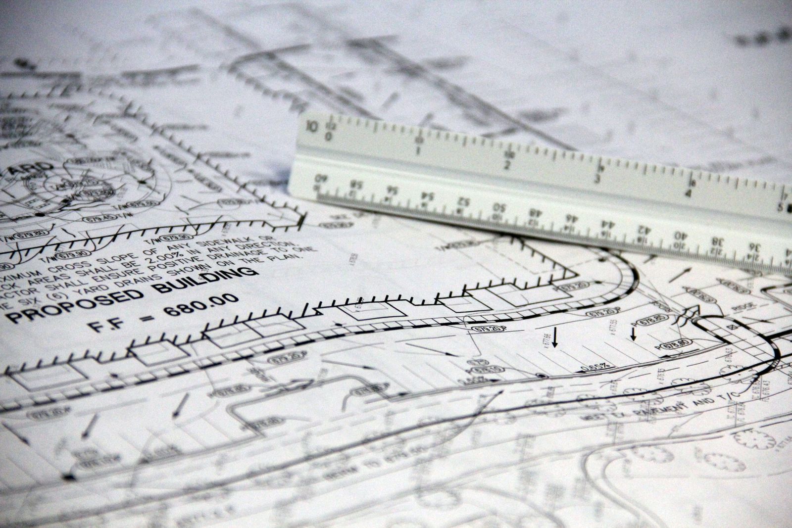 A close-up of technical site drawings with a white scale ruler laid across them